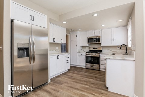 A modern kitchen with a stainless steel refrigerator and white cabinets.