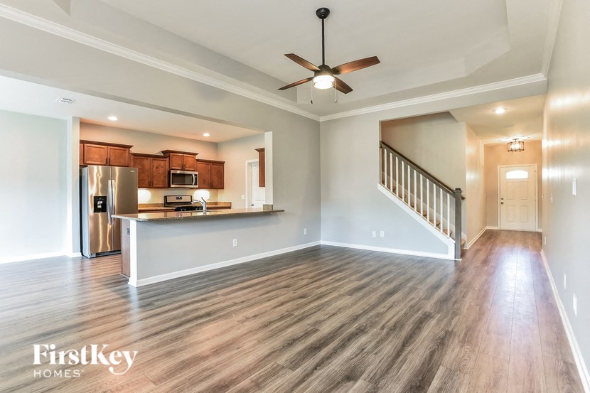 an empty living room and kitchen with a ceiling fan