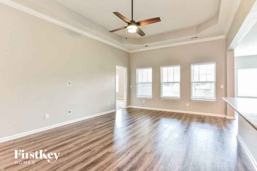 an empty living room with wood floors and a ceiling fan