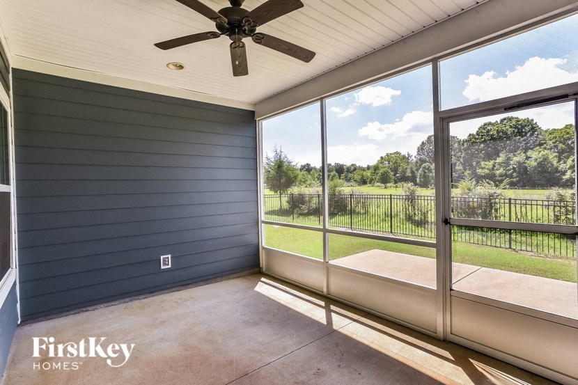 the screened porch has a view of the yard and a ceiling fan