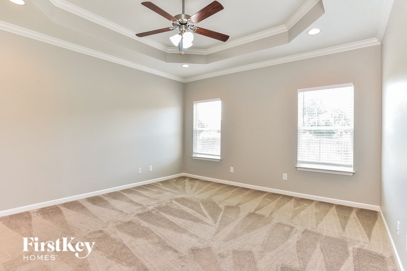 an empty room with a ceiling fan and two windows