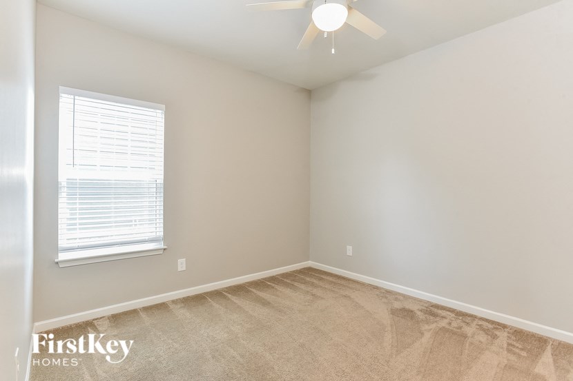 an empty bedroom with a ceiling fan and a window