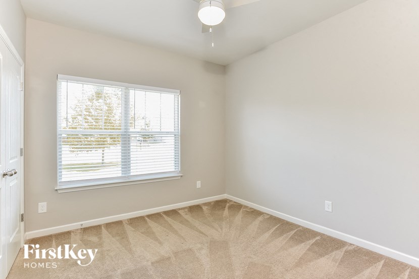 an empty bedroom with a window and a carpeted floor