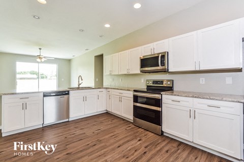 A kitchen with white cabinets and a FirstKey Homes logo.