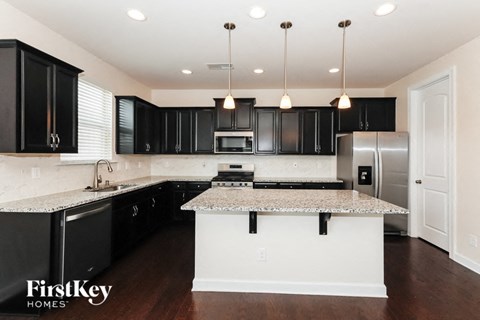 an updated kitchen with black cabinets and granite counter tops and a white island with black