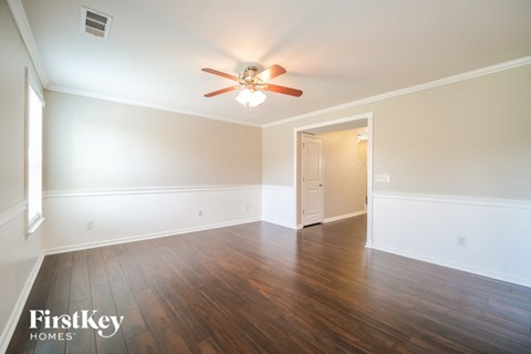 A room with a ceiling fan and wooden floors.