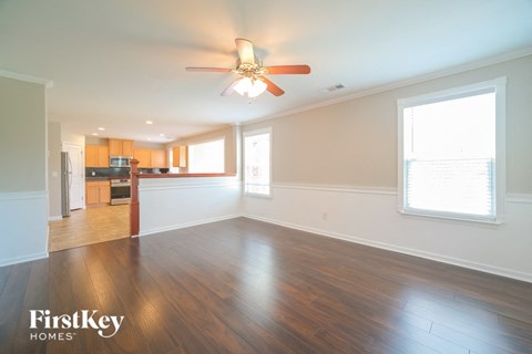 A spacious room with wooden floors and a ceiling fan.