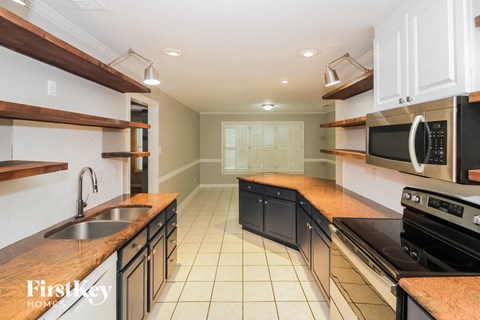 A kitchen with a sink, stove, and microwave.
