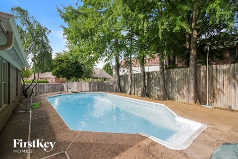 A small pool surrounded by a fence and trees.