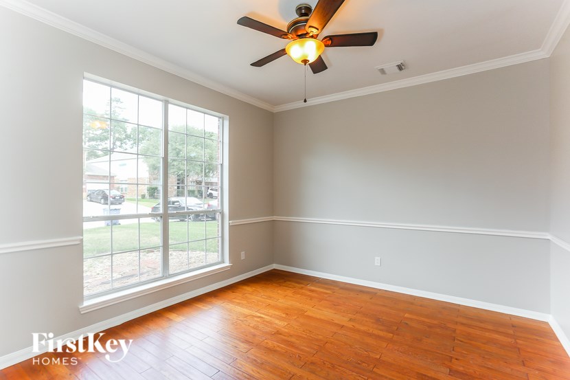 A room with a ceiling fan and wooden floors.