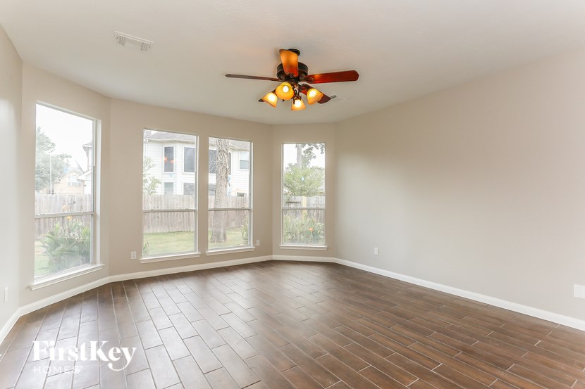 A room with a ceiling fan and wooden flooring.