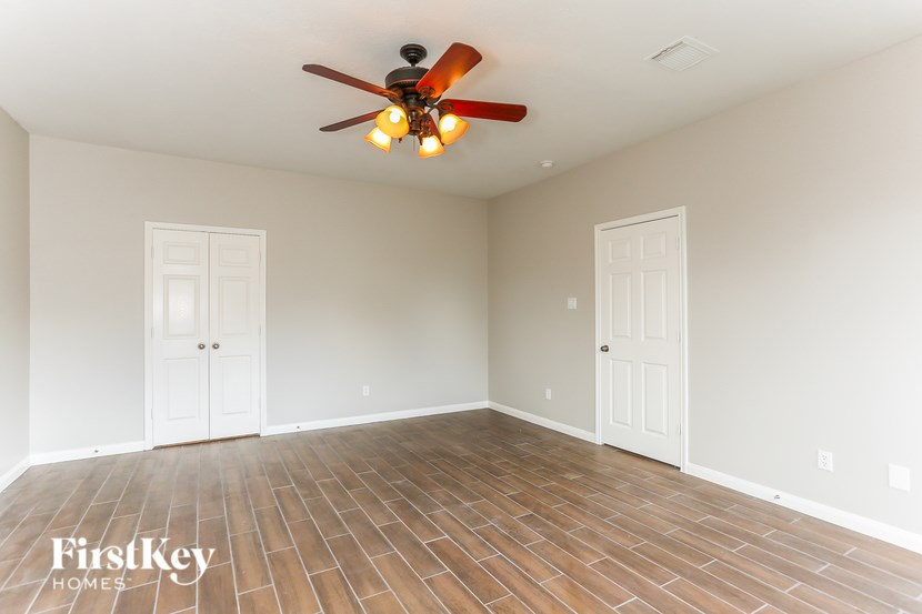 A room with a ceiling fan and wooden flooring.