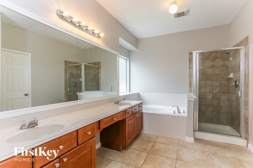 A bathroom with a vanity, a mirror, and a walk-in shower.