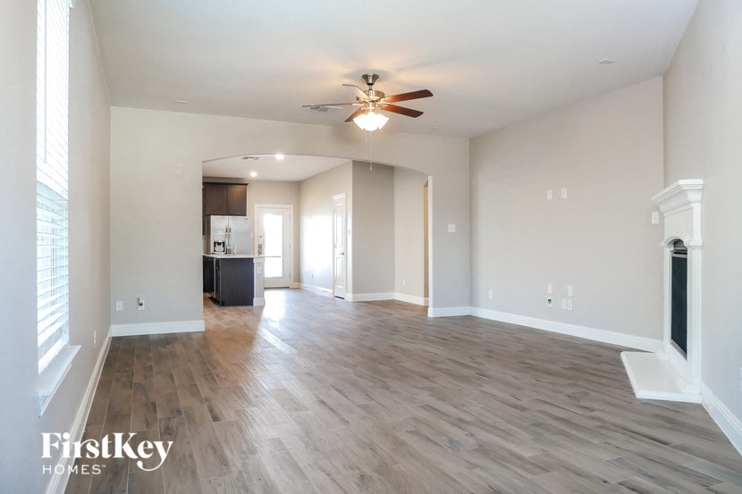 an empty living room with a ceiling fan and a kitchen