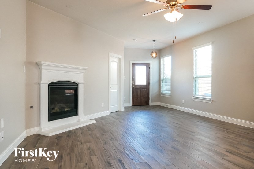 an empty living room with a fireplace and a ceiling fan