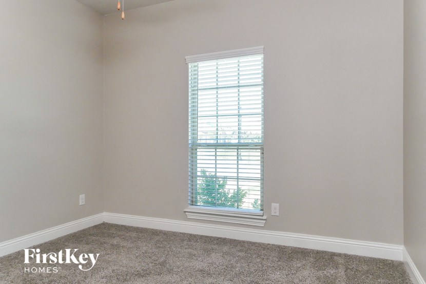a bedroom with a window and a carpeted floor