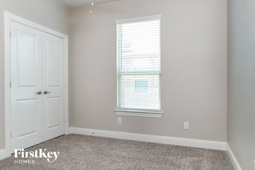 a bedroom with a door and a window and a carpeted floor