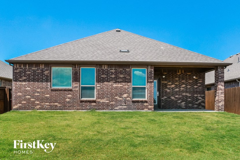 a brick house with blue shutters on a lawn