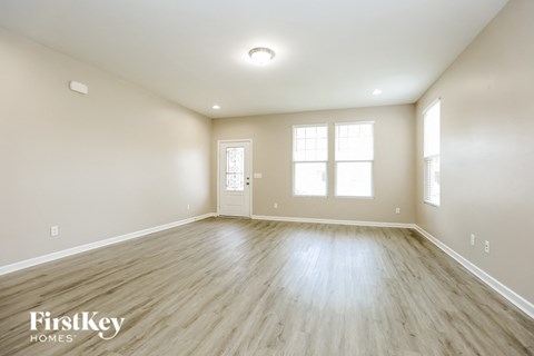 an empty living room with wood floors and white walls
