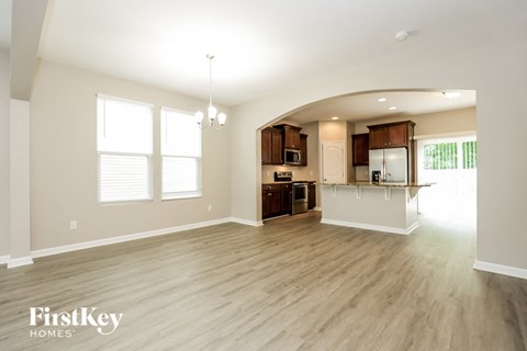 an empty living room and kitchen with wood flooring