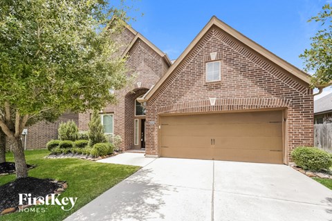an empty driveway in front of a brick house with a garage door