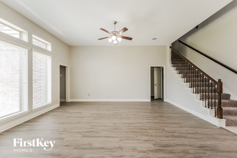 an empty living room with a staircase and a ceiling fan