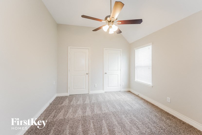 a living room with a ceiling fan and a carpet