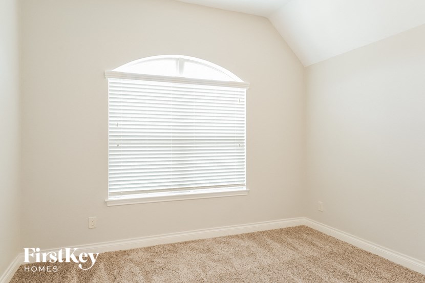 the second bedroom has a large window and carpeted flooring