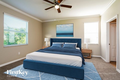A bedroom with a blue bed and a ceiling fan.