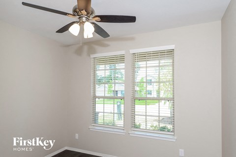 a bedroom with a ceiling fan and three windows