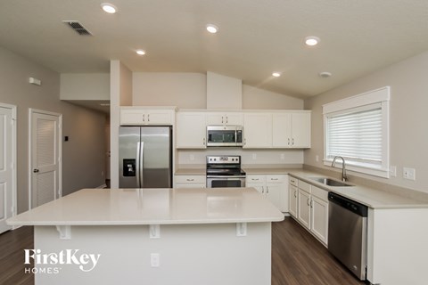 a white kitchen with stainless steel appliances and white counter tops