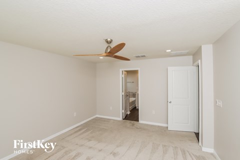 a living room with a ceiling fan and a door to a bathroom