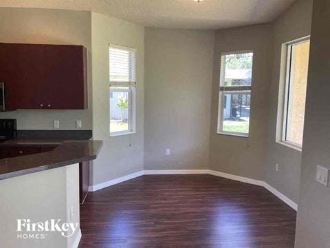 A room with wooden floors and a kitchen area with a counter.