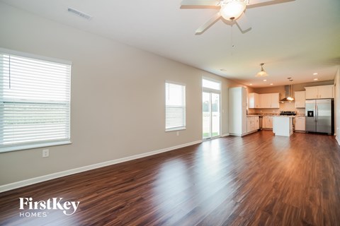 A spacious room with wooden floors and a ceiling fan.