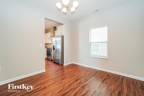 A kitchen area with wooden floors and a refrigerator.