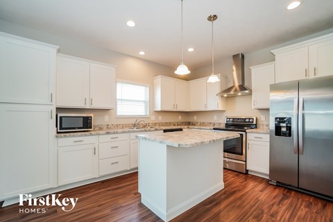 A kitchen with white cabinets and a wooden island.