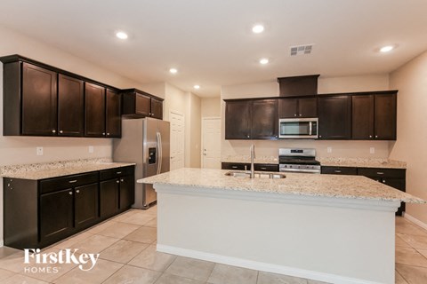 A kitchen with a white counter top and dark brown cabinets.