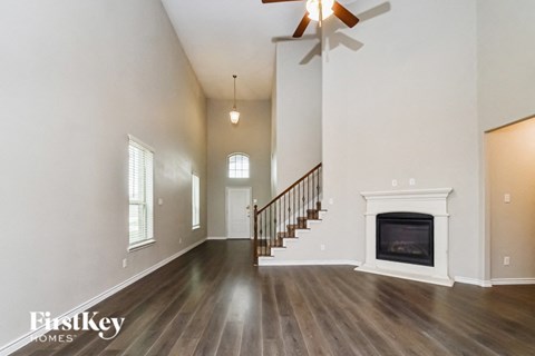 A spacious living room with a fireplace and a staircase.