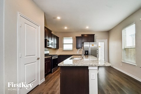 A kitchen with a white countertop and dark brown cabinets.