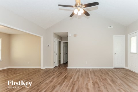 A spacious room with a ceiling fan and wooden flooring.
