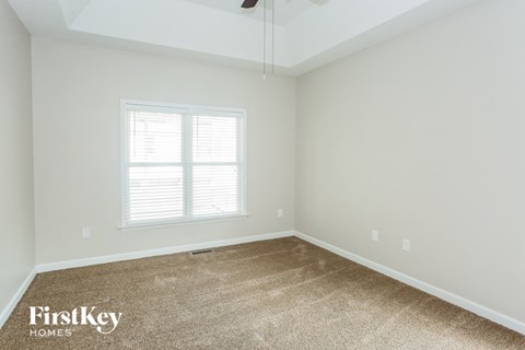 the bedroom of a home with carpet and a window