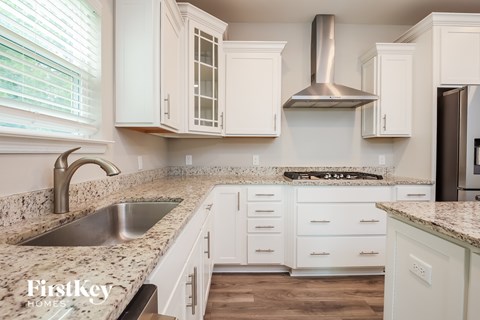A kitchen with white cabinets and a granite countertop.