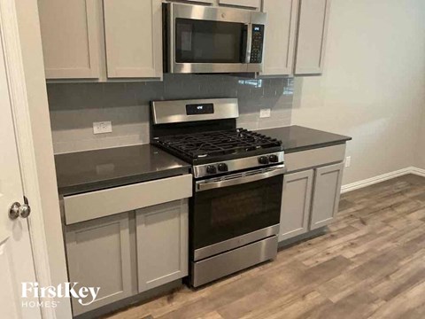 A modern kitchen with a stove top oven and microwave above it.
