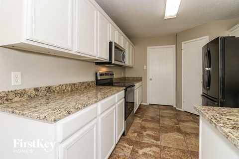 a kitchen with white cabinets and a black refrigerator