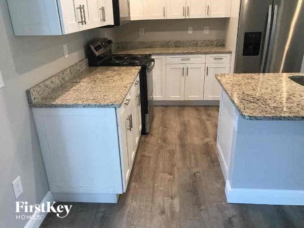 a kitchen with white cabinets and marble counter tops