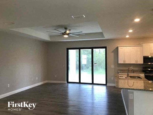 a empty living room with a kitchen and a ceiling fan
