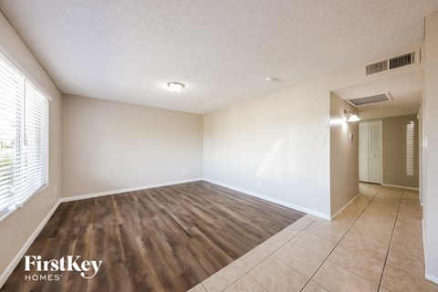 a spacious living room with wood flooring and white walls