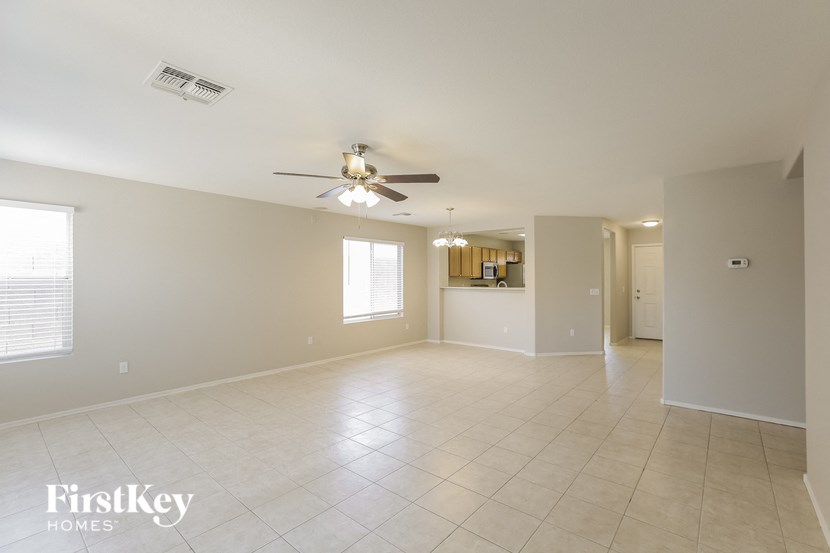 an empty living room with a ceiling fan and tiled floor
