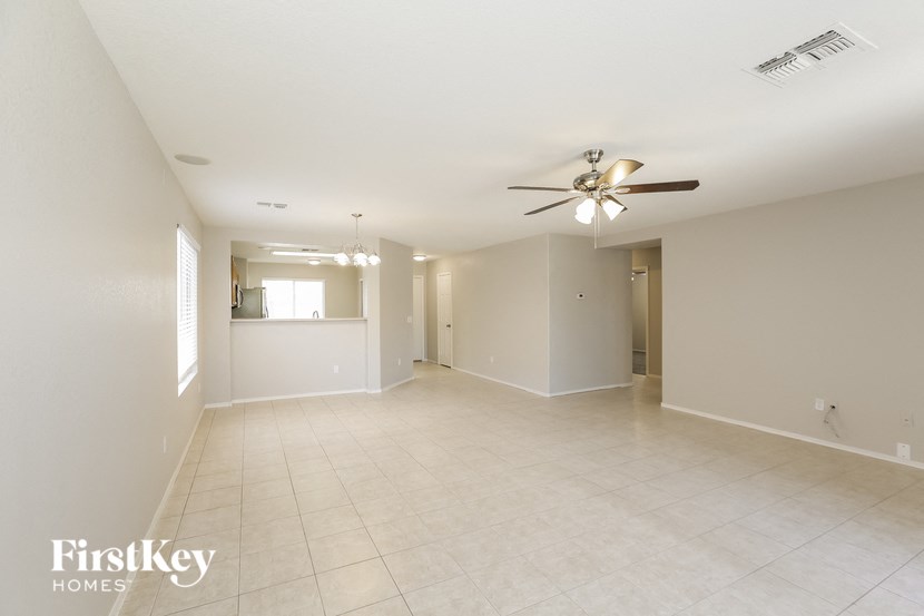 an empty living room with a ceiling fan and a tiled floor