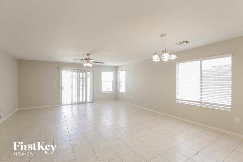 an empty living room with a ceiling fan and a window